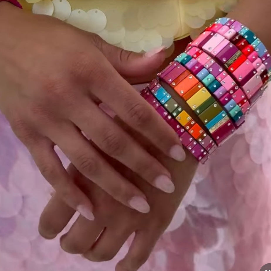 Mujer muestra pulseras Dominó apiladas en colores de verano