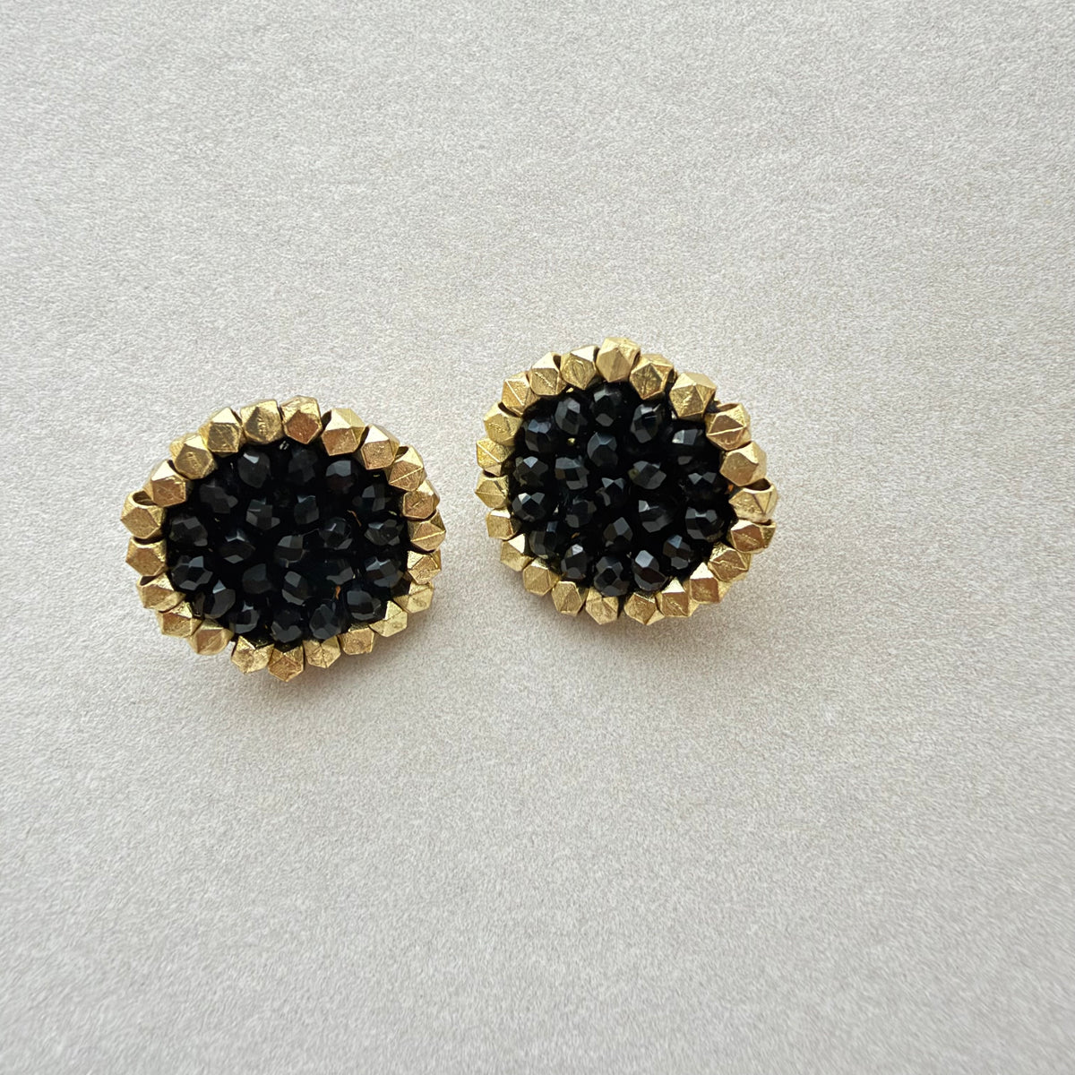 Par de Aros Trisha con cuentas facetadas negras y borde dorado