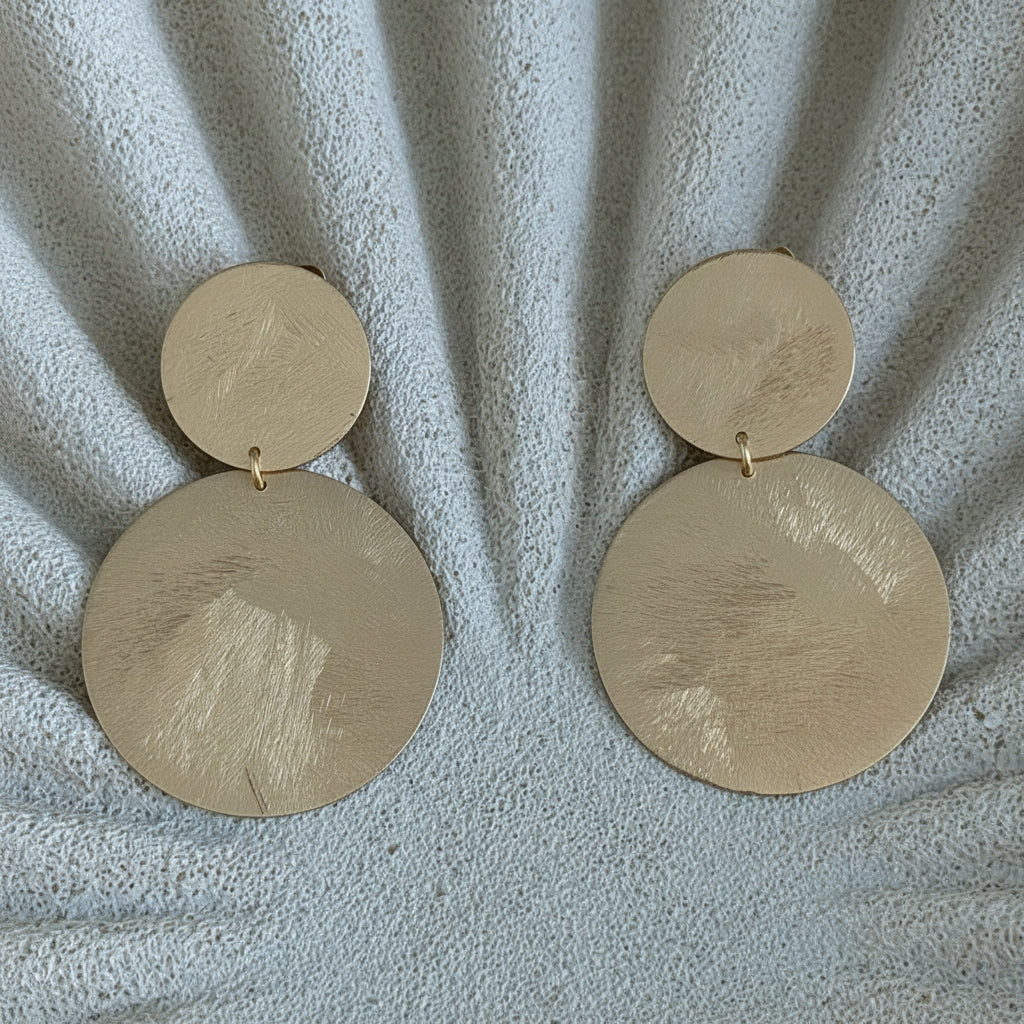 Aros Bianca con baño de oro de 18 quilates y diseño de doble disco satinado. Hechos en Brasil, elegantes, livianos y de 6 cm de largo.