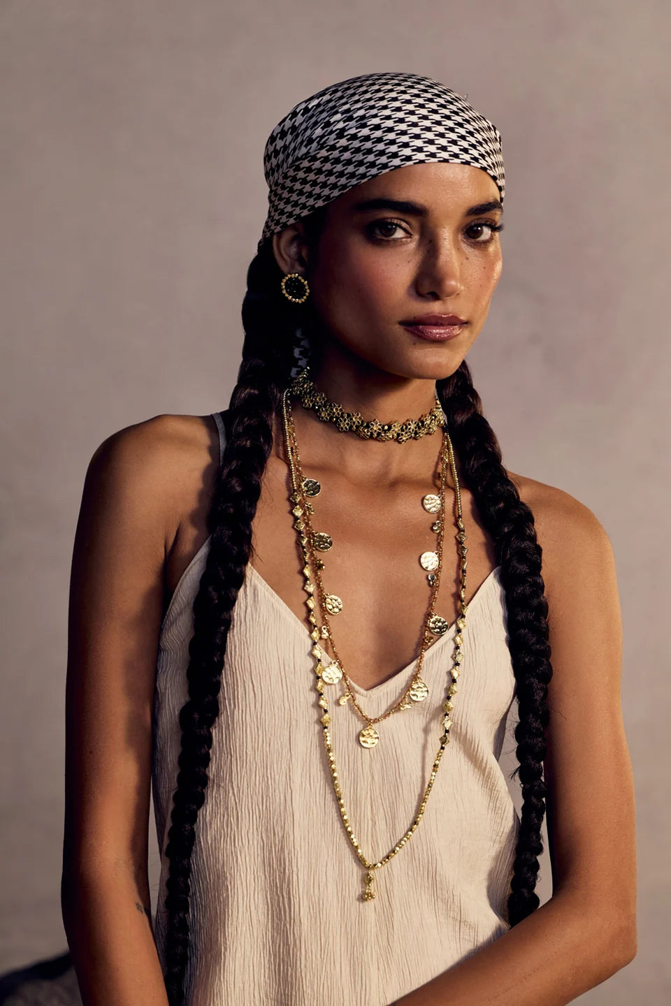 Modelo con el Collar Mishika dorado al cuello, combinado con collares largos sobre un top claro