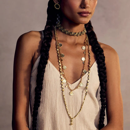 Modelo con vestido claro, pañuelo estampado y collares dorados superpuestos