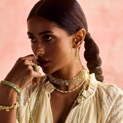 Modelo con el Collar Ayra Layering de House of Tuhina al cuello, hileras de cuentas doradas con gotas de color