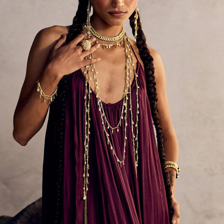 Modelo con la mano levantada mostrando la pulsera Nayra Dorada, combinada con collares y aros dorados.